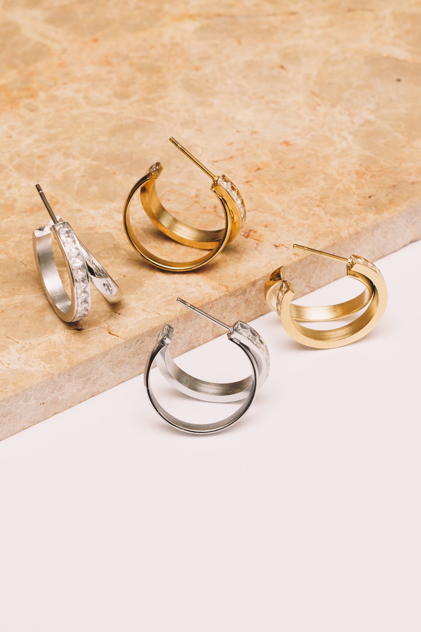 silver split hoop earrings and gold split hoop earrings on marble and white background